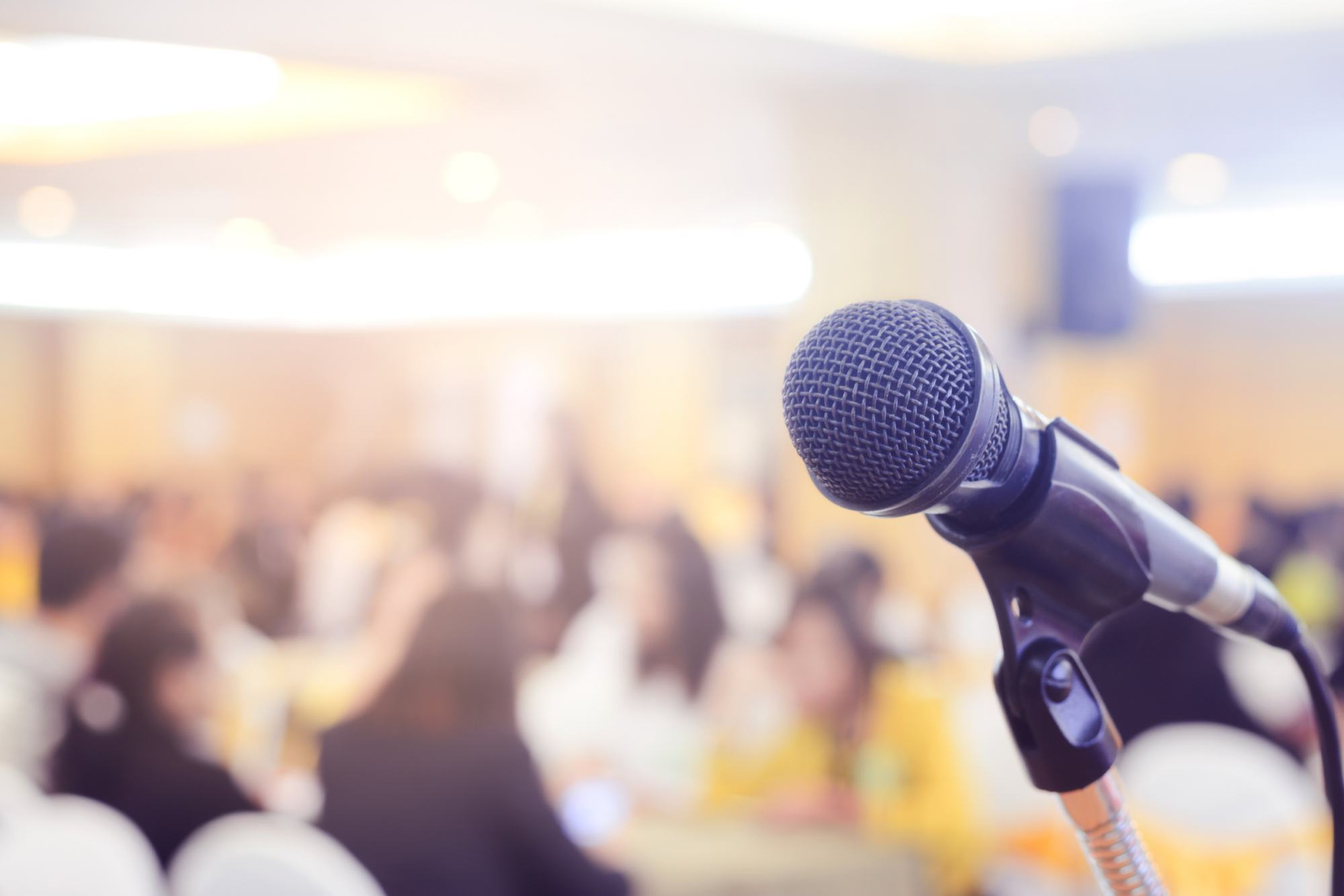 a microphone stands before a full conference room