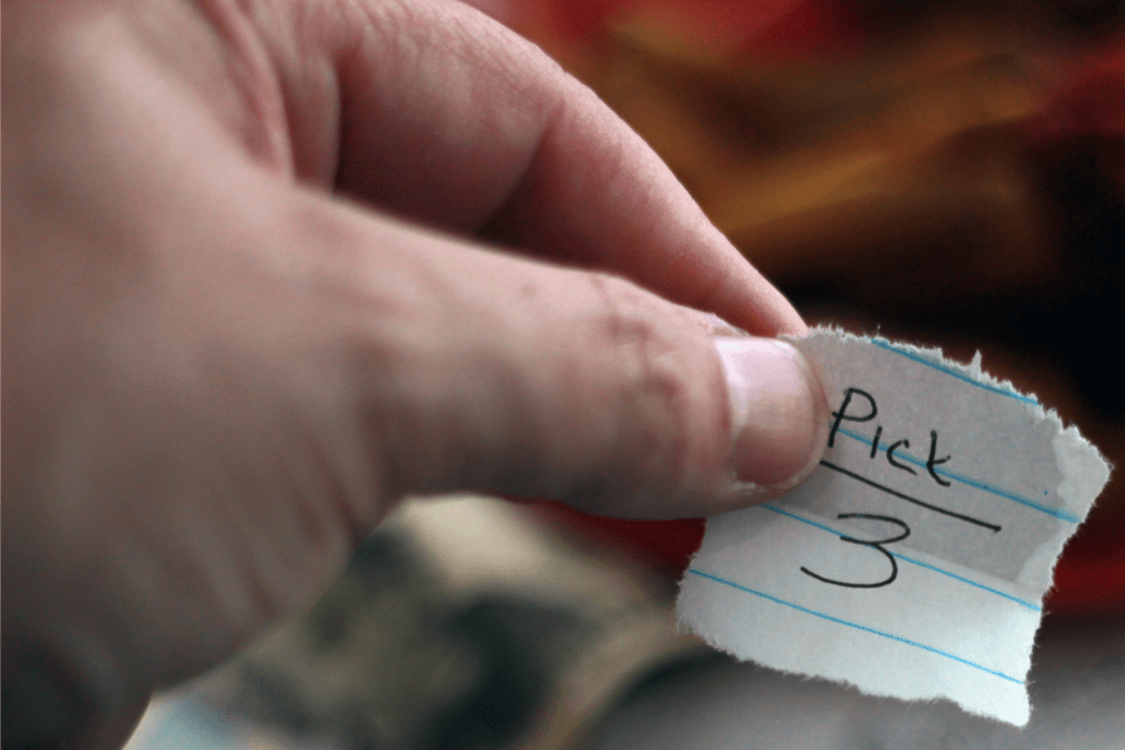 a close-up of a hand holding a small piece of paper labeled pick 3