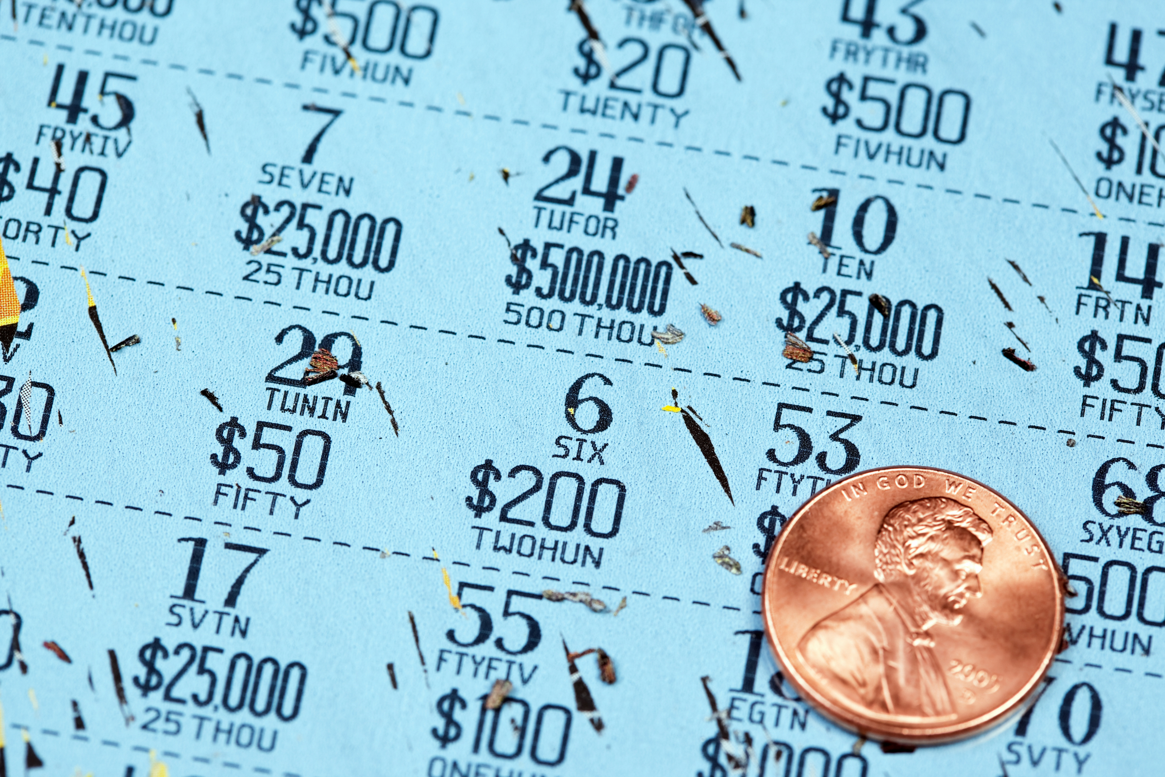 a lottery scratch-off ticket fully scratched with a shiny US penny