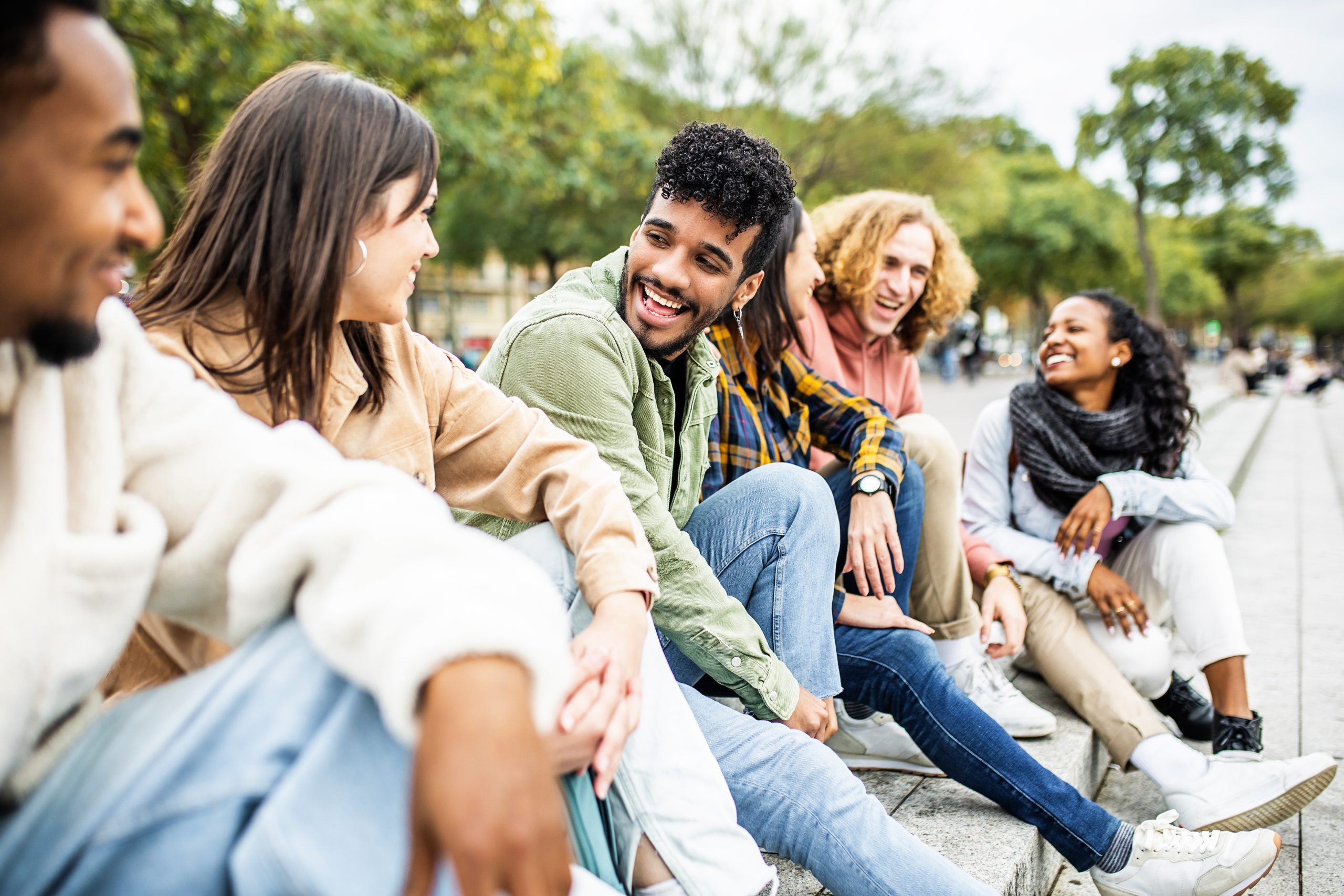Happy group of trendy young people laughing together sitting outdoor
